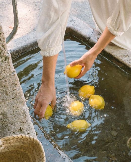 Hands rinsing lemons in a stone fountain